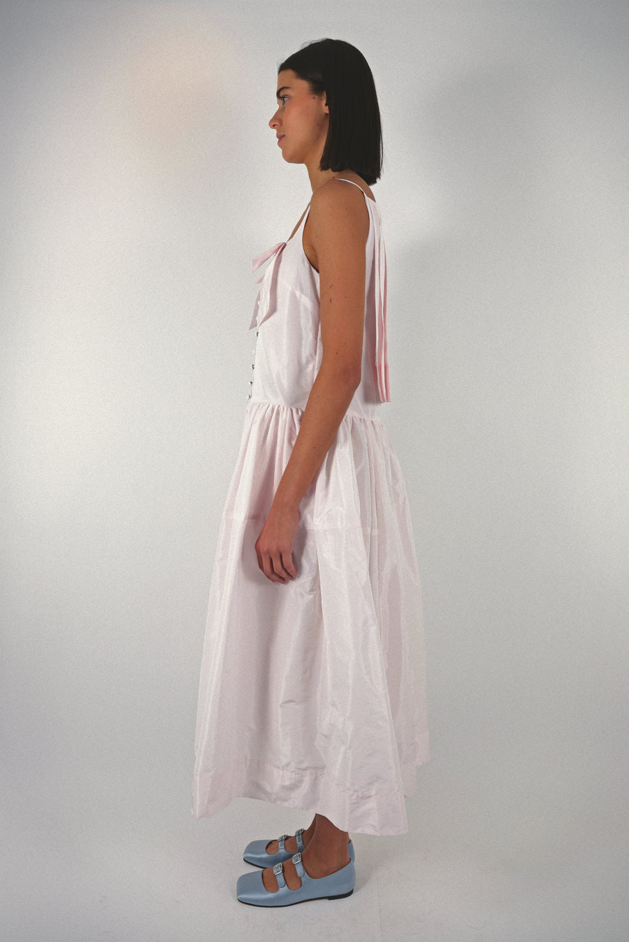 Midi length dress in blush pink taffeta with buttons and cape detail at back on model