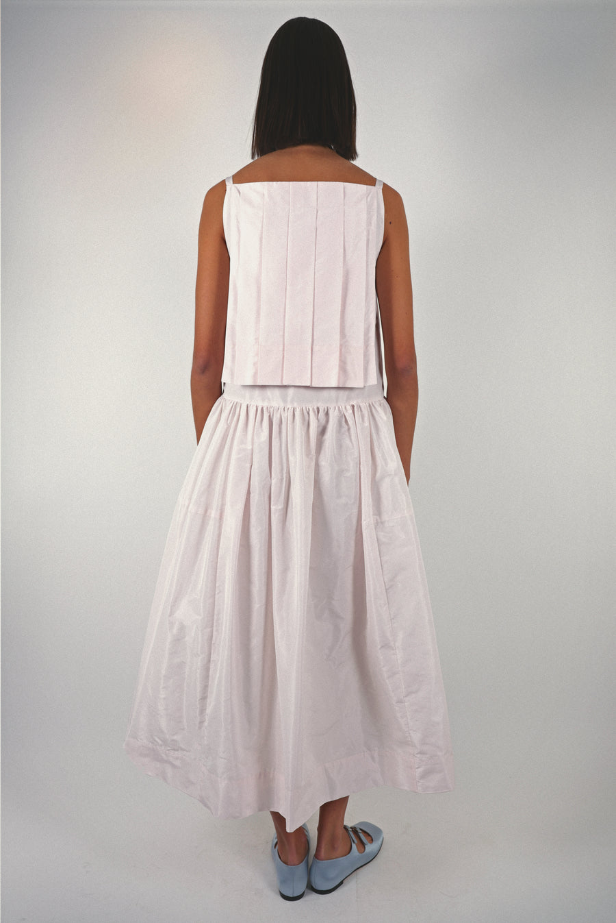 Midi length dress in blush pink taffeta with buttons and cape detail at back on model