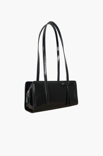 A black rectangular handbag with a bow detail on the side against a white background