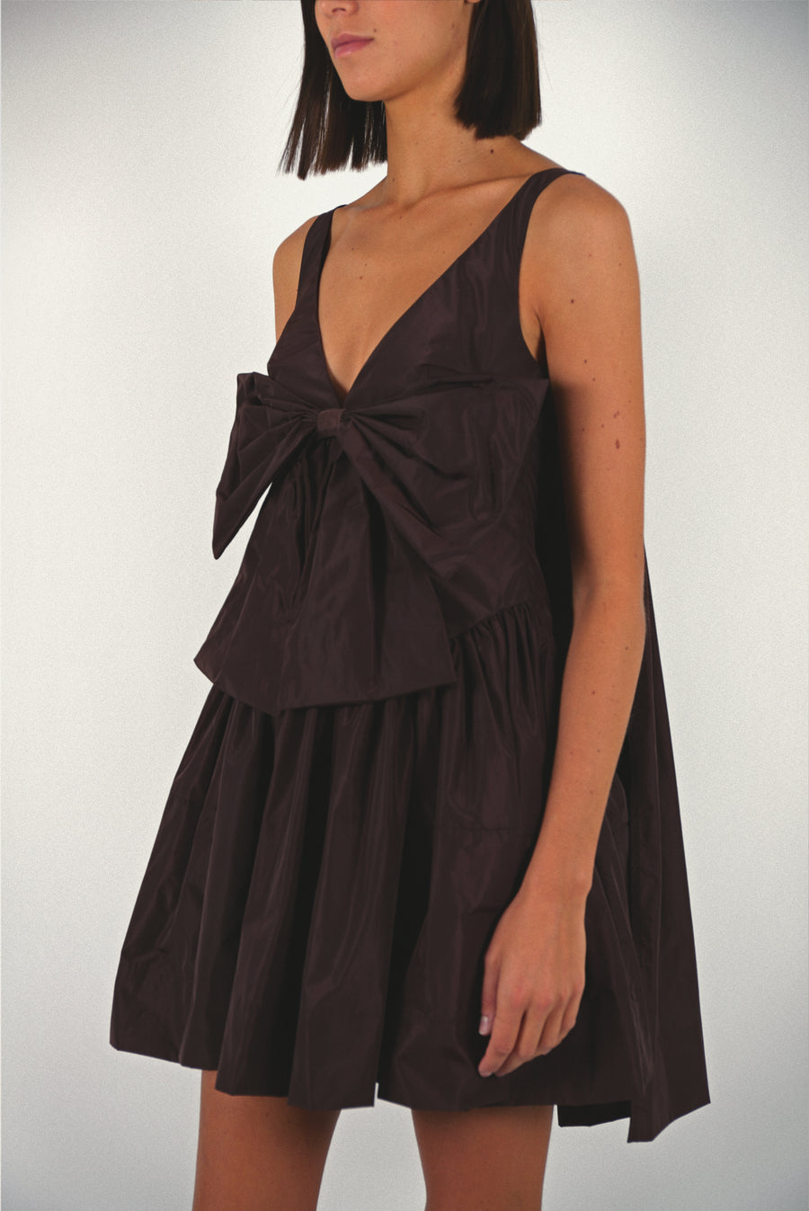 Mini dress in coffee brown taffeta with bow at front and cape in back on model