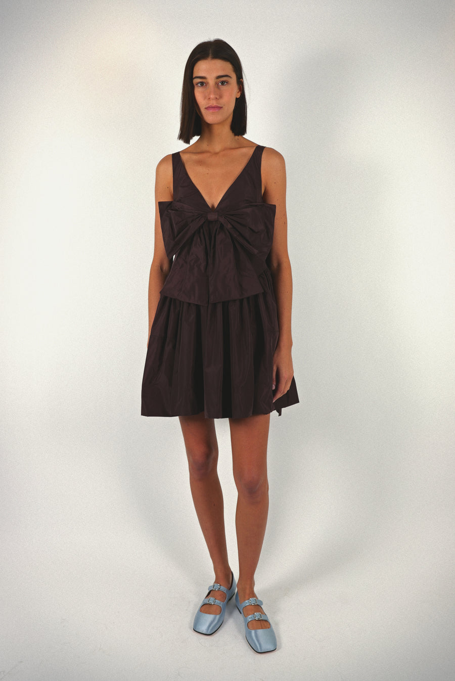 Mini dress in coffee brown taffeta with bow at front and cape in back on model
