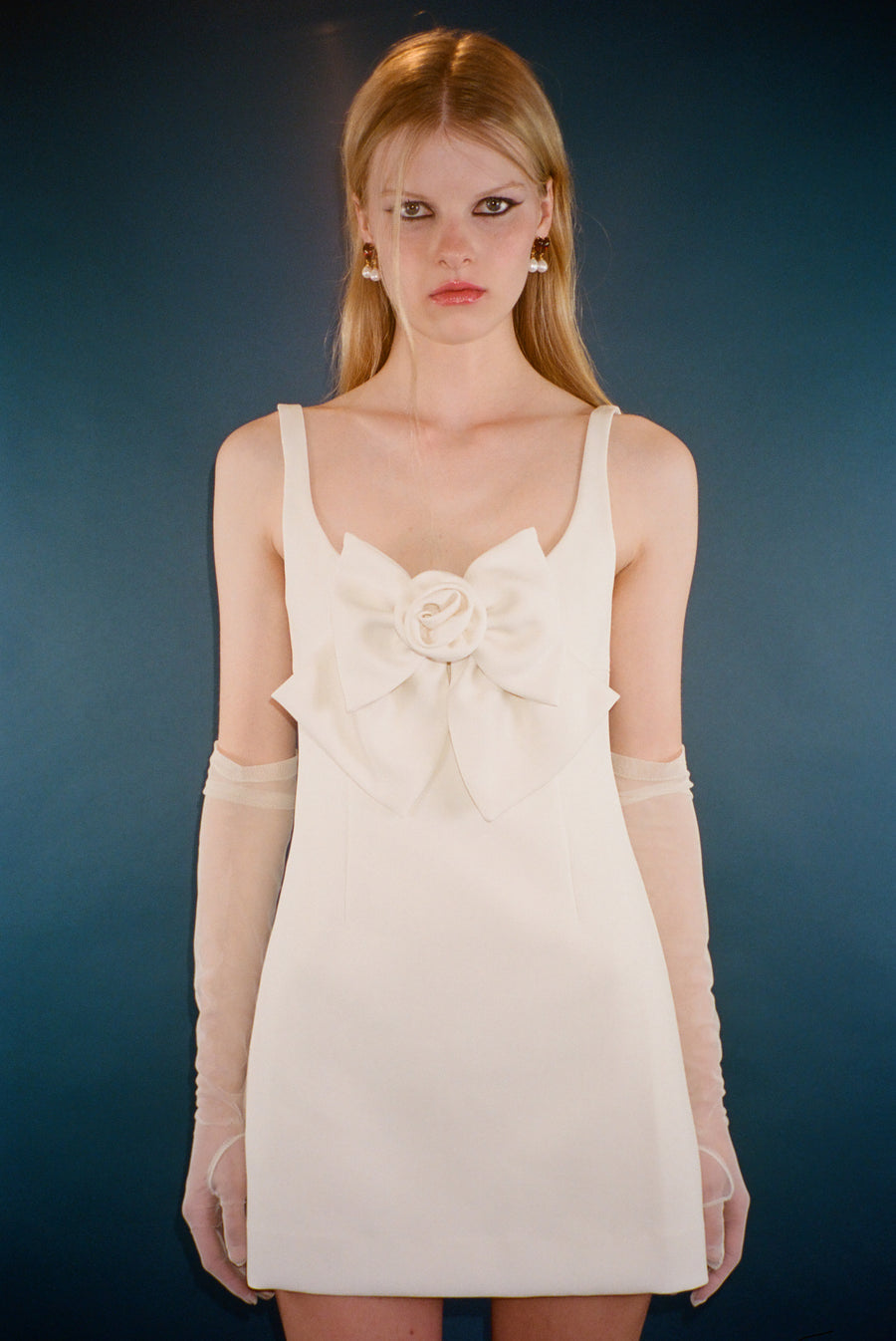 Tailored mini dress in cream with oversized bow at front on model