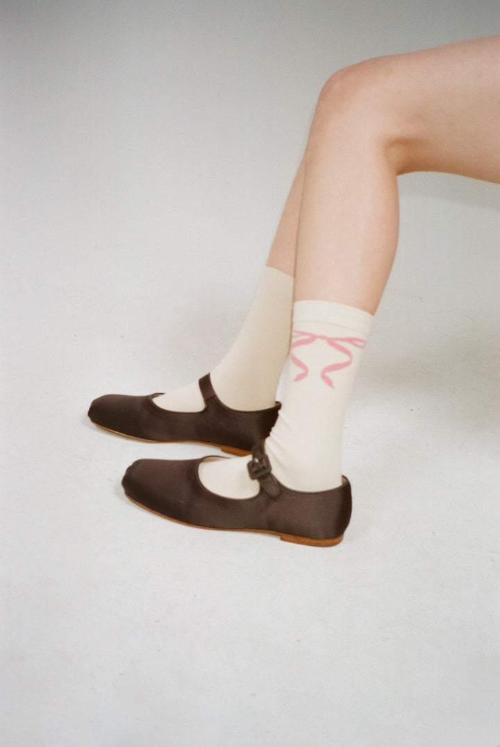 Butter yellow crew length socks with pink bows on either side on model