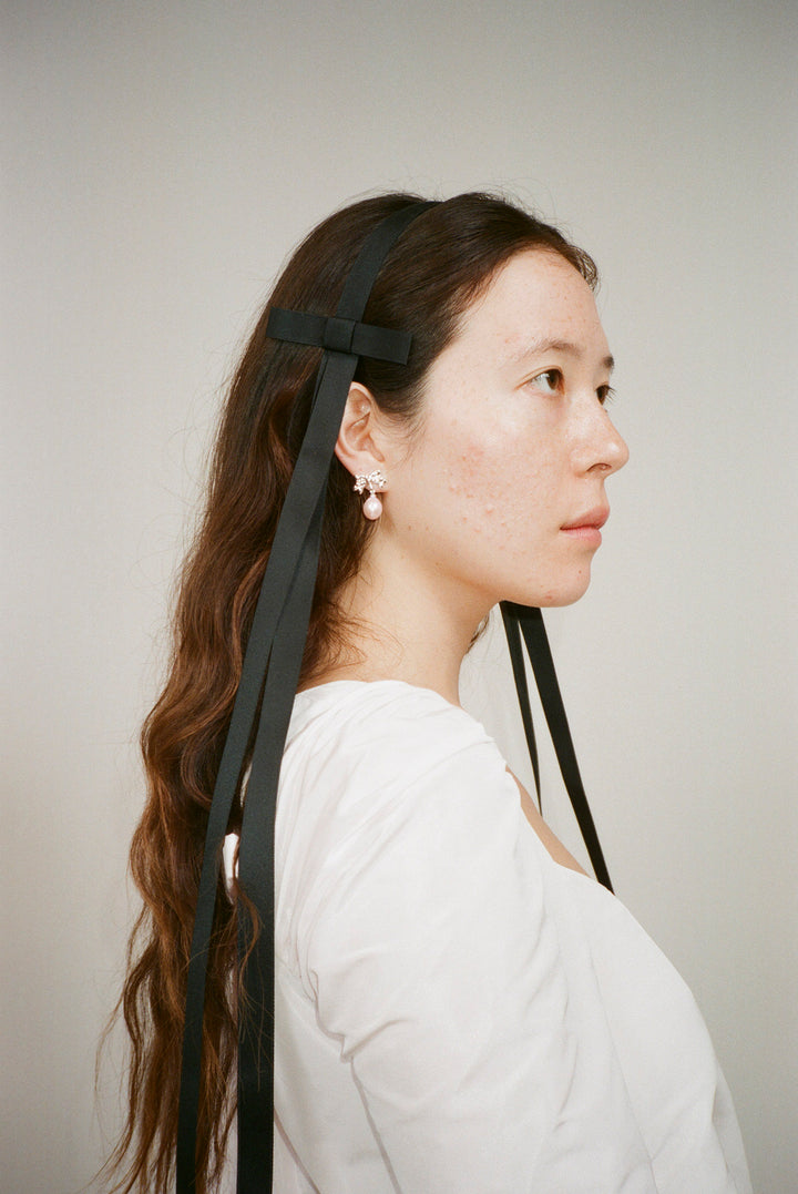 Black headband with elongated bows at sides on model