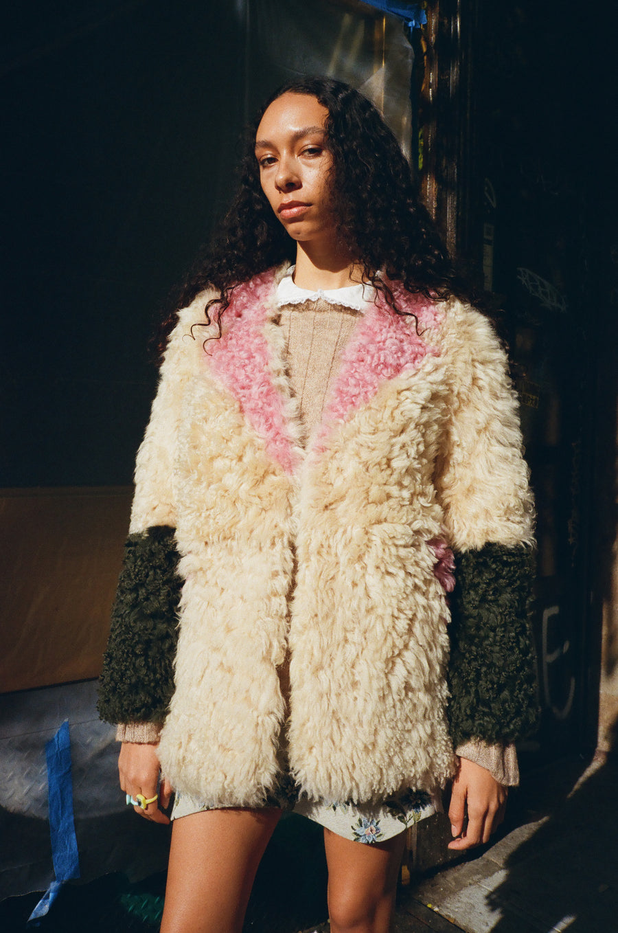 Shearling coat with contrast pink, cream, and green details on model